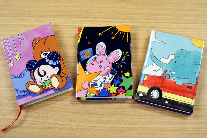 入選したイラストを使って、オリジナルミニブックを製本してもらいました！

（写真左）スクサモソーン チュティモンさんの作品「好きなもの（この子にとっては可愛いもの)に囲まれながら本を読もうというテーマで描きました」
（写真中央）倉持 楓さんの作品「幼少期に情報量の多い絵本を読んでワクワクした記憶があったので、細かいモチーフをたくさん置いて、ごちゃっとさせました」
（写真右）キン セイさんの作品「子供向けの象の世界旅行の物語をイメージして描きました」
